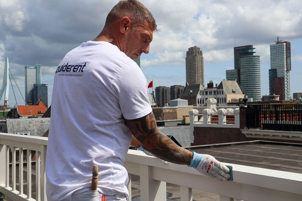 Zuiderent-schilder die een houten balustrade afwerkt